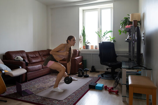 Young woman doing fitness at home watching online tutorials on tv