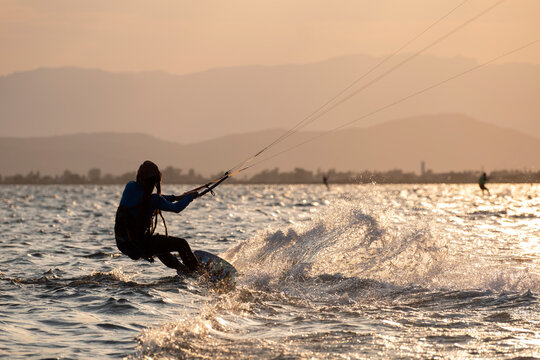 Kitesurfer carving the water at sunset backlight