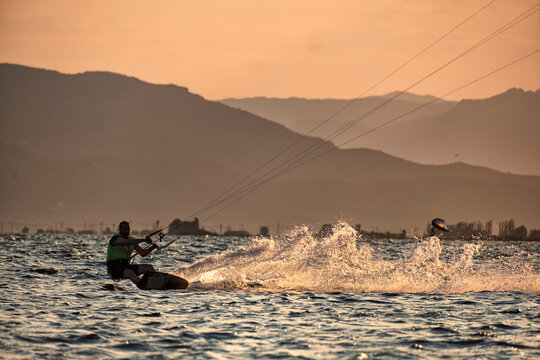 Kitesurfer carving the water at sunset backlight