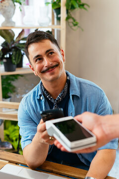 Attractive man using smartphone to pay in restaurant
