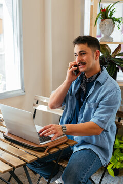 Man talking on the phone and working at a coffee shop 

