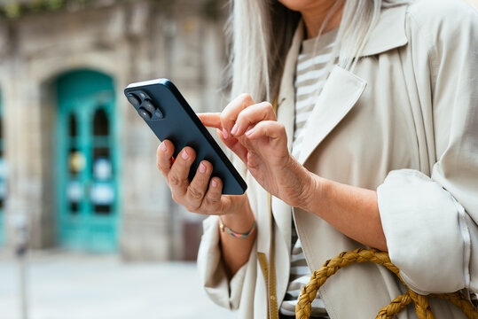 Anonymous Woman with grey hair Using Smartphone on Town Street