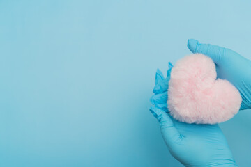 Blue Gloved Hands Holding Pink Fluffy Heart On Blue Background, Place For Logo, Place For Text, Charity