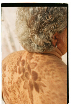 woman from behind with flower shadows on her skin 