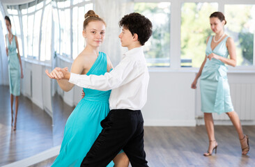 Fototapeta premium Dance teacher teaches a girl and boy couples ballroom dancing