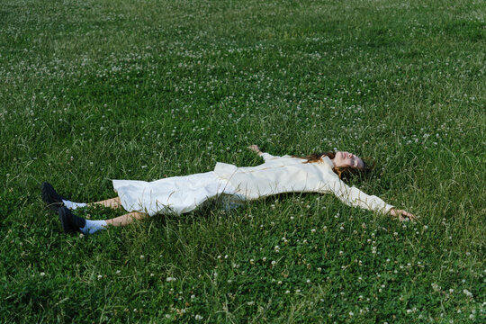 Woman in White Outfit Lying in Green Meadow