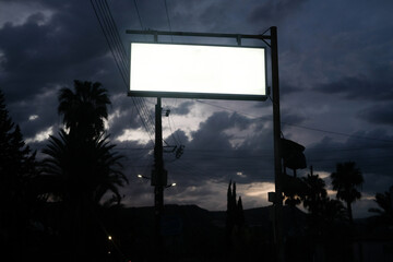 Blank Billboard Stands Against a Stormy Evening Sky in a City