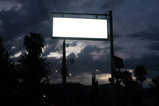 Blank Billboard Stands Against a Stormy Evening Sky in a City