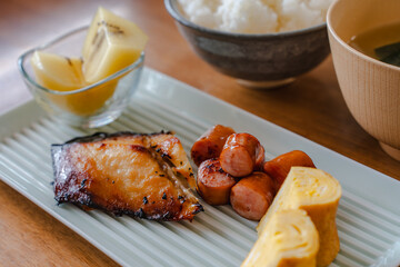 Traditional Japanese breakfast with grilled fish, rice, miso soup, tamagoyaki and fruit
