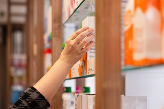 Hand reaching for product on pharmacy shelf