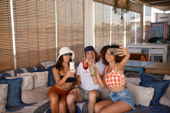 Group of cheerful friends taking selfies in a bar