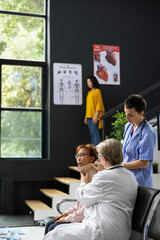 Female nurse fitting cervical neck collar on injured patient at clinic, offers spinal support in...