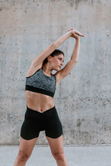 Fototapeta premium Young Hispanic woman stretching and exercising in sportswear outdoors in urban area in Latin America