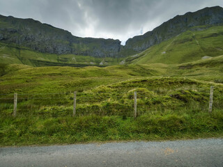 Beautiful scenery of Horse shoe drive in County Sligo, Ireland. Mountains covered with green juice grass and cloudy sky. Wool sheep scattered on mountain slop. Popular travel area.