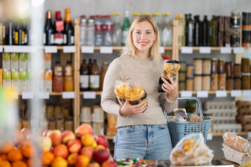 Young female shopper buying package of pasta in grocery store