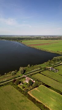 Aerial view of a rural landscape with a central road, water body, irrigated fields, and scattered houses. The scene highlights agricultural planning and natural integration.