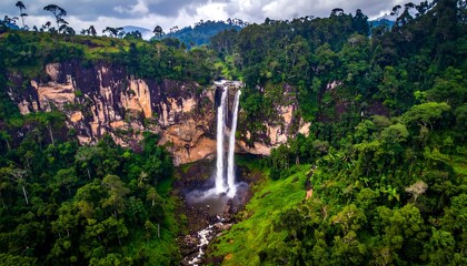 Obraz premium Dramatic waterfall cascading down a cliff face in a lush green valley