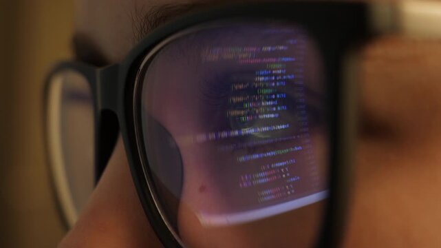 Software Developer, Artificial Intelligence and Programming. Coding Encryptions Scroll Past Screen in Reflection of Software Engineers Eyeglasses. Young Woman Behind Computer Coding in Dark Room.
