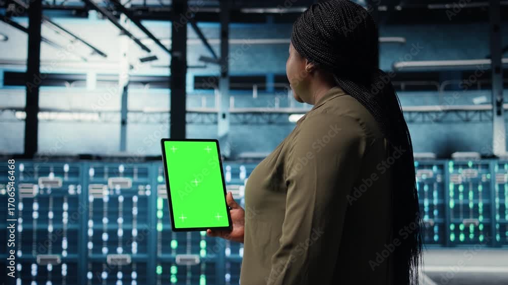 Poster data center specialist monitors data center metrics on green screen tablet to enhance operational ef