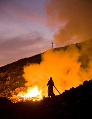 Silhouette figure by a bonfire at night on a hill