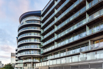 Low angle view of a modern glass block of apartments in a riverside developemnt in London at dusk in winter