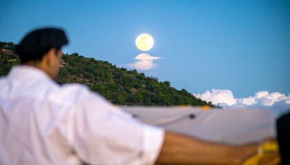 Person in white shirt and cap facing away, moonlit landscape