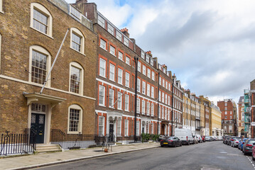 Row of old town houses along a street in a central London on a cloudy winter day. England, UK.