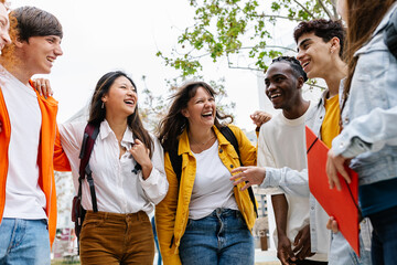 Young group of multiracial teenage students laughing and hanging out at high school campus. Youth and education lifestyle concept