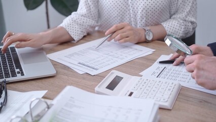 Female bookkeeper or auditor is working on finances papers with a colleague, using magnificent...
