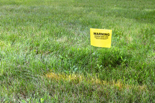 Gas line marker in the yard. Yellow utility flag placed in the yard of a house