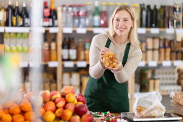 Positive female seller offers to buy delicious fresh grapes