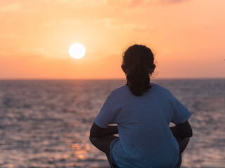 Woman enjoying a tranquil and reflective sunset.