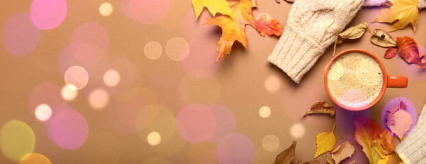 Composition with cup of coffee, sweater and autumn leaves on brown background