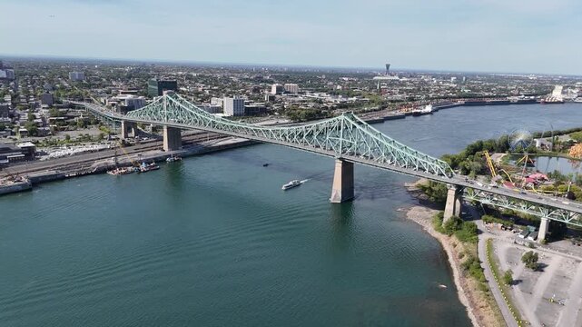 Drone approaches Jacques Cartier Bridge in Montreal, passing over a cruise ship, with Olympic Stadium in the distance, panning down to reveal moving traffic