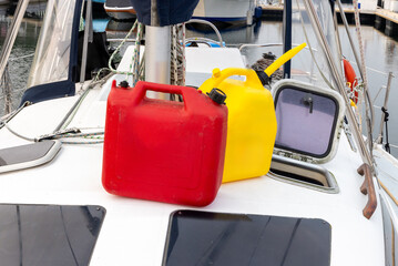 Red and yellow plastic jerry fuel cans by the mast of a sailboat
