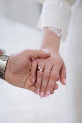 Close up of groom holding brides hand with engagement and wedding rings on her finger