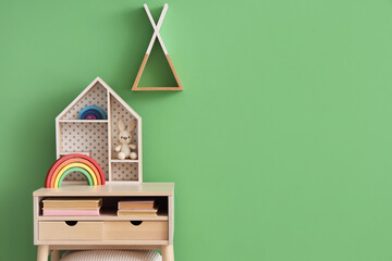 Table with children's toys and books near green wall