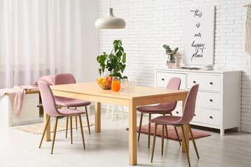 Table with fruits in bowl and jug of juice in interior of dining room