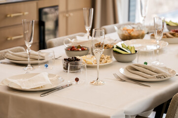 Elegant dining table set with champagne flutes, plates, napkins, and assorted appetizers, ready for a festive celebration or family gathering in a modern home.