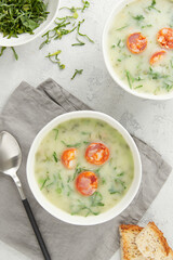Two bowls of Portuguese style soup Caldo Verde with bread on gray background