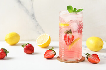Glass of drink with ice cubes, strawberry and lemon slices on marble background