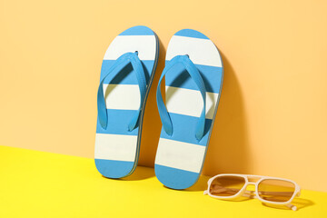 Composition with stylish beach shoes and sunglasses on beige background, closeup