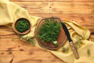 Bowl and cutting board with fresh green dill on wooden background