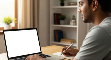 Fototapeta premium Over shoulder view of white blank empty mockup laptop screen for advertising. Indian adult male student having virtual meeting, training online call, educational webinar, chatting or working at home