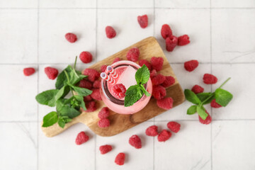 Glass of cold cocktail with raspberry on white tile background