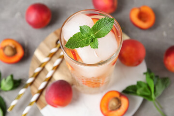 Glass of tasty cold cocktail and apricots on grey grunge background, closeup