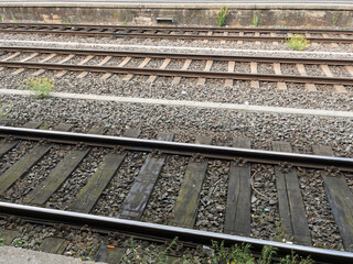 Naklejka premium Abandoned Train Tracks Surrounded by Weeds and Gravel