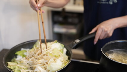 野菜を炒める女性