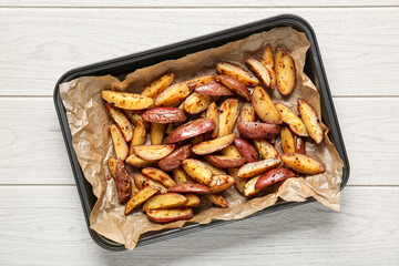 Baking dish with tasty baked potatoes on white wooden background