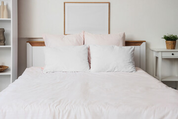 Bed with stylish pink bedding, shelving unit and bedside table in bedroom at home